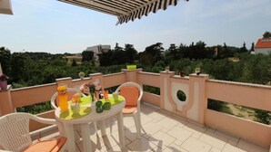 A balcony with a table and chairs, a bottle of Fanta, and a vase with flowers. - Apartments Danijela Novalja (Novalja)