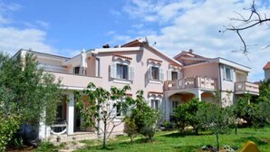 A two-story house with a balcony, surrounded by a well-maintained garden and a playground. - Apartments Danijela Novalja (Novalja)