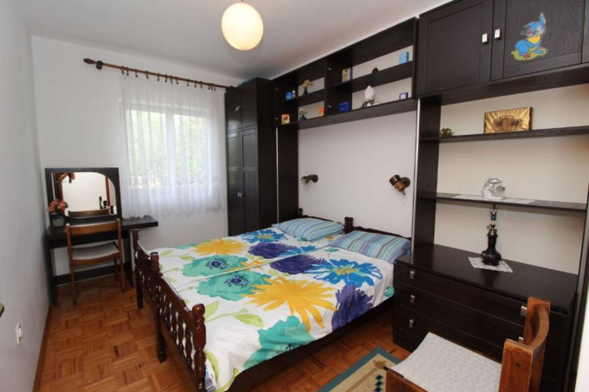 Une chambre à coucher comprenant un lit, un bureau, une chaise, une armoire et une étagère avec divers objets.
