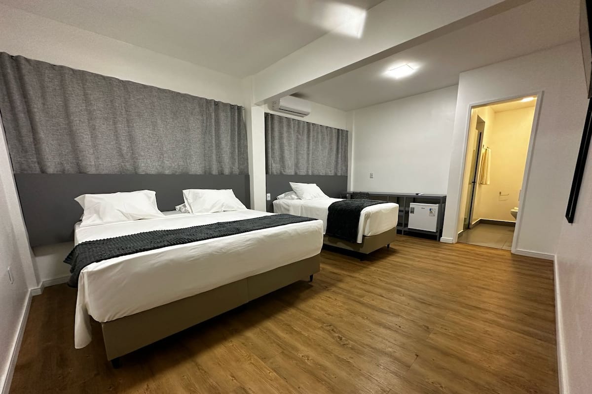 A hotel room with two beds, a desk, and a small kitchenette.