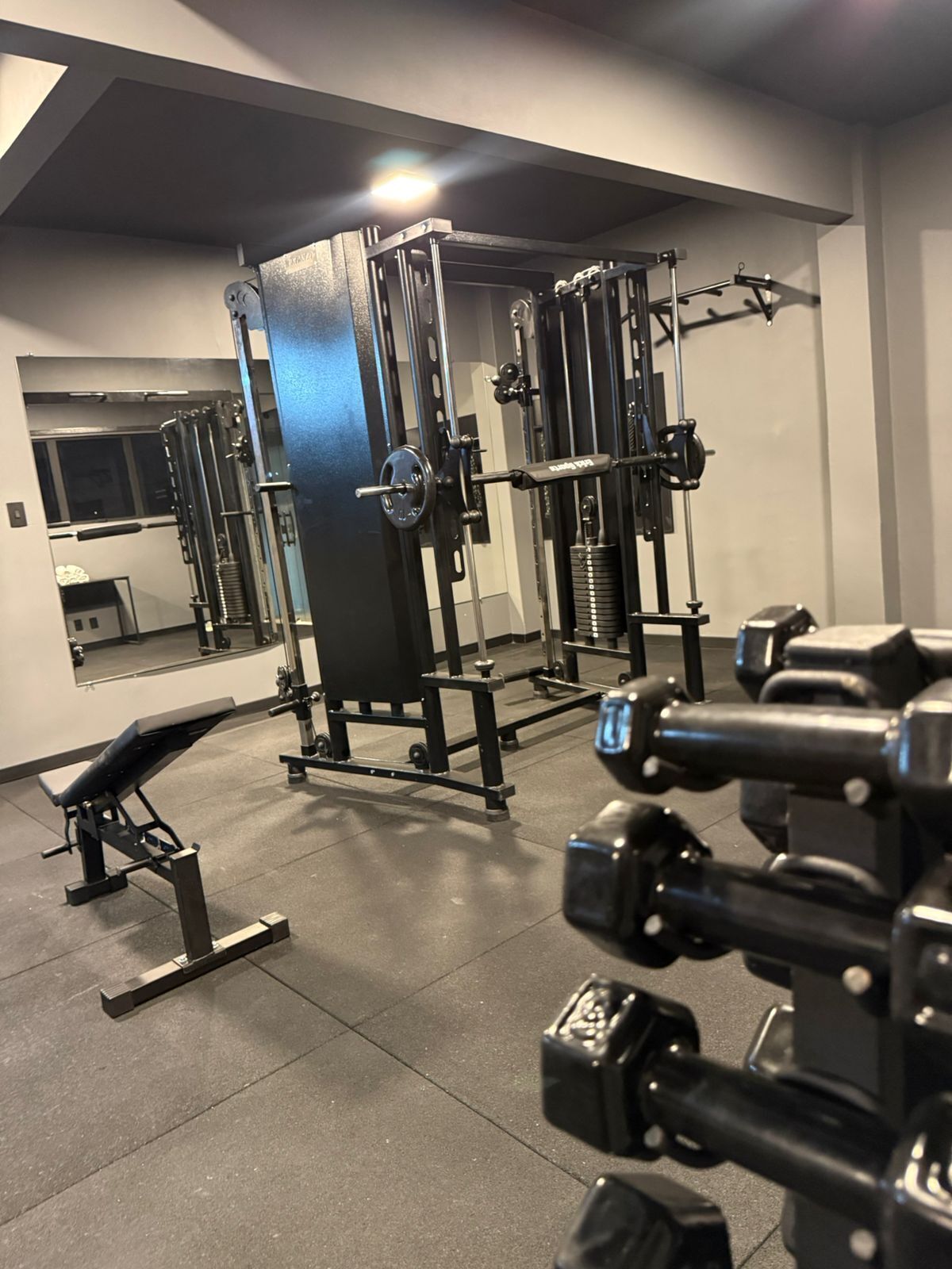 Ein Fitnessstudio mit Gewichthebern, einer Bank und einem Spiegel an der Wand.