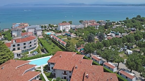 A residential area with a large swimming pool, terraced houses, and a view of the sea. - Residence Sant Elena A19 by Wonderful Italy (Peschiera del Garda)