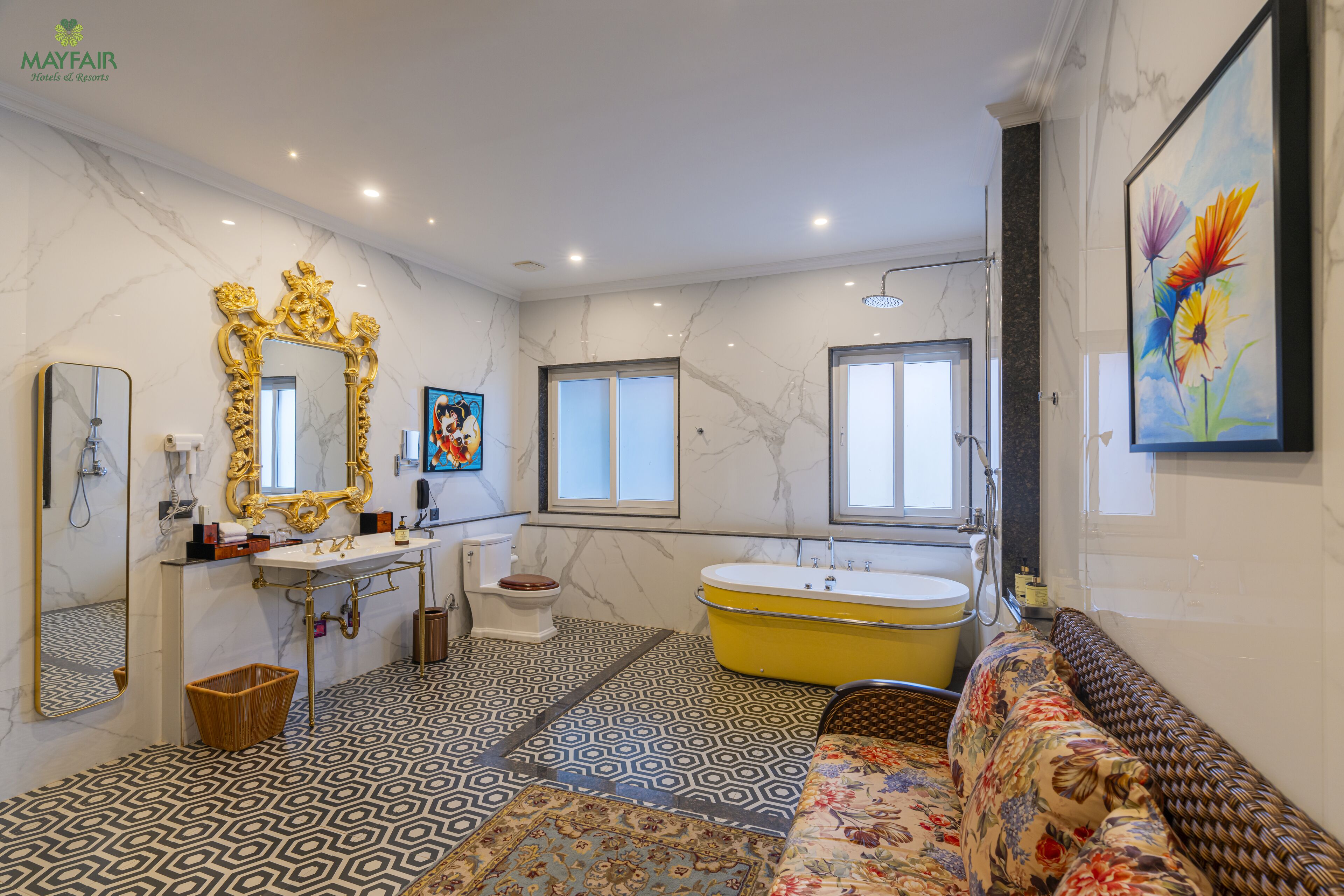 A bathroom with a marble floor, a bathtub, a sink, a toilet, and a large mirror.