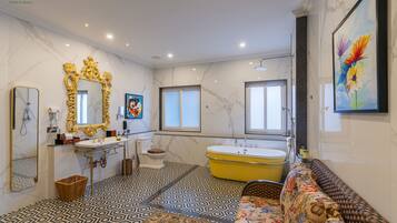 A bathroom with a marble floor, a bathtub, a sink, a toilet, and a large mirror.