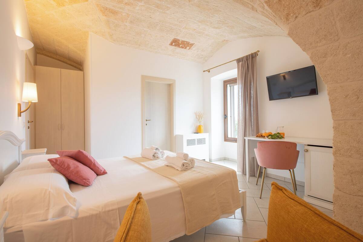 Ein Hotelzimmer mit Bett, Schreibtisch, Stuhl und Fernseher an der Wand.