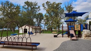 Une aire de jeux avec des balançoires, un toboggan et une structure d’escalade.