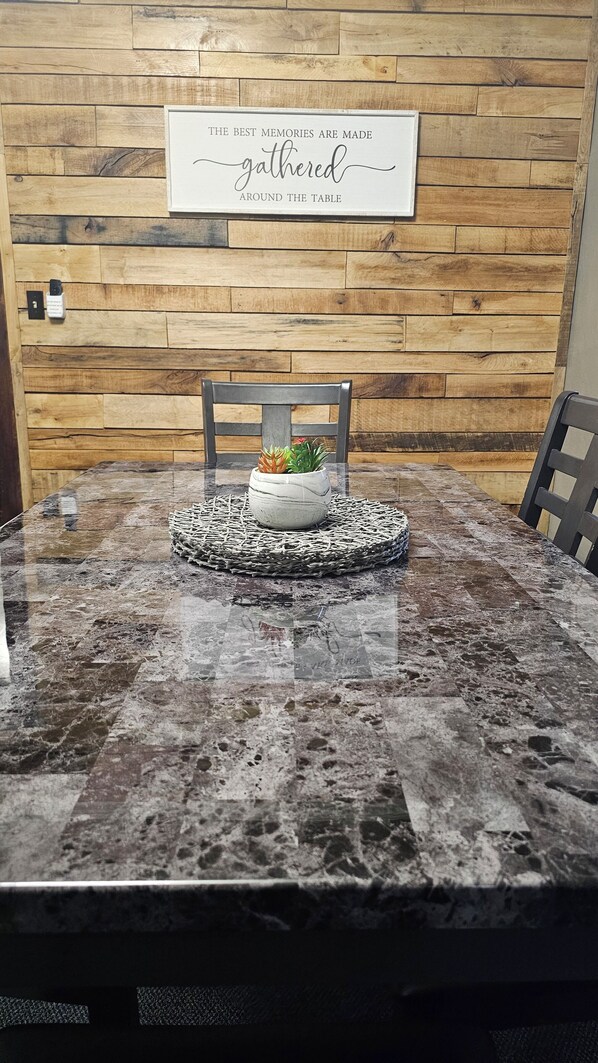 A dining table with a marble top, surrounded by chairs, and a sign on the wall above.