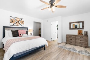 Cozy retreat with a large bed, dresser, and ceiling fan.