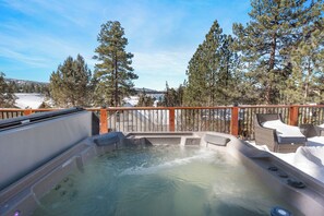 Relax in a hot tub surrounded by serene pine trees and a breathtaking view.