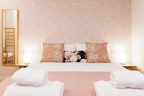 Une chambre d’hôtel avec un lit, deux tables de chevet, un miroir et un mur orné d’un motif géométrique.