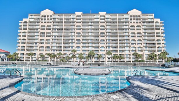 A large hotel with multiple balconies and a central swimming pool.
