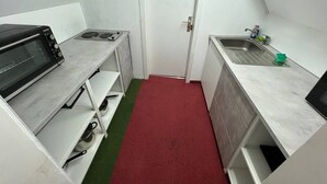 A compact kitchenette with a microwave, stove, and sink. - Room in Guest Room - Pension Forelle - Double Room n01 (Forbach)