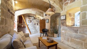 Un interior rústico de piedra con un sofá, una mesa de madera y una lámpara colgante.