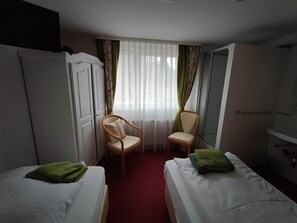 A hotel room with two beds, a chair, a radiator, and a window with sheer curtains. - Room in Guest Room - Pension Forelle - Double Room 01 (Forbach)