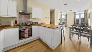 Una cocina moderna con armarios blancos, una campana extractora de acero inoxidable y una encimera de madera.