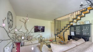 Ein modernes Wohnzimmer mit Treppe, einer roten Vase und einem Fernseher.