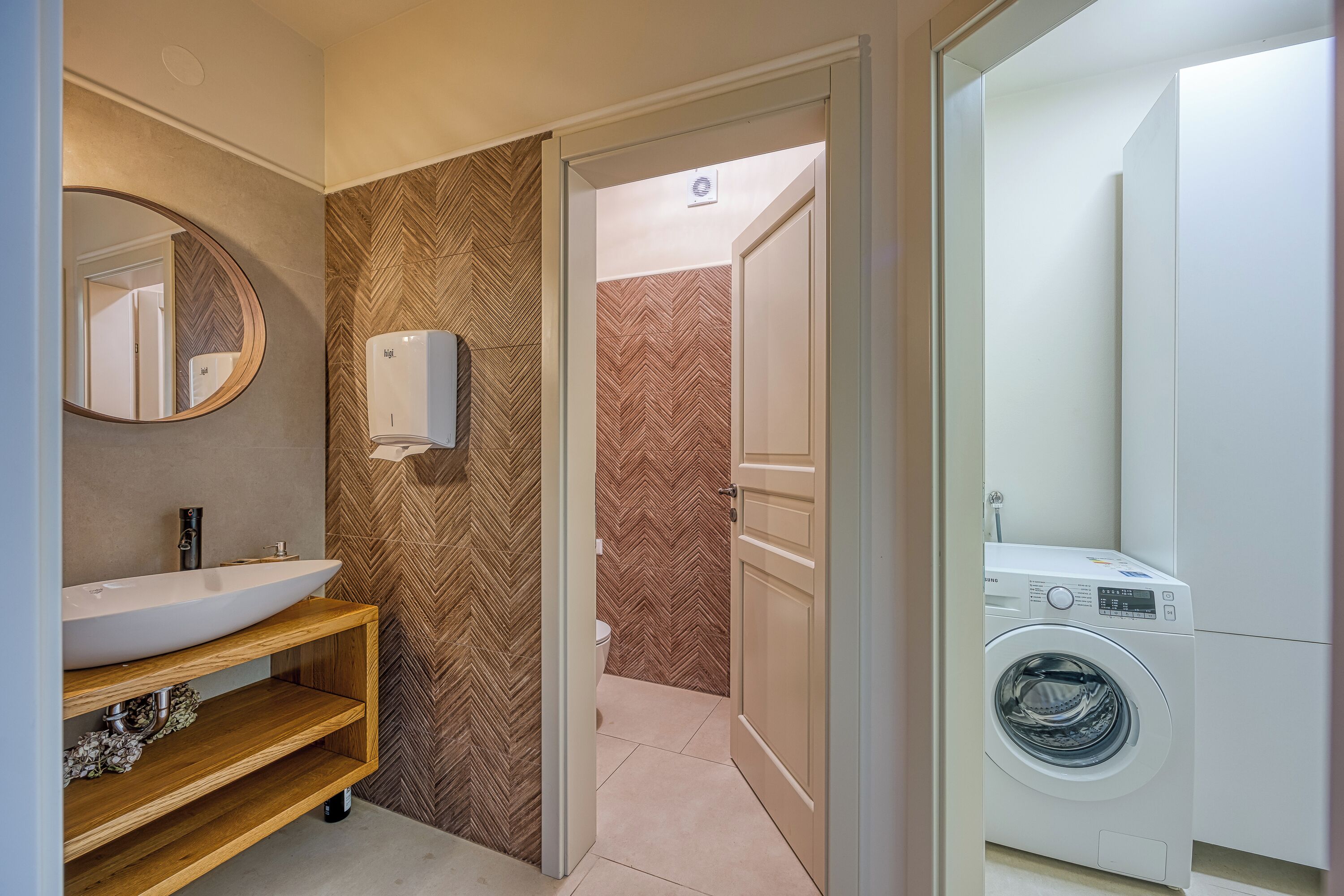 A modern bathroom with a wooden vanity, a large mirror, a built-in sink, and a wall-mounted heater.
