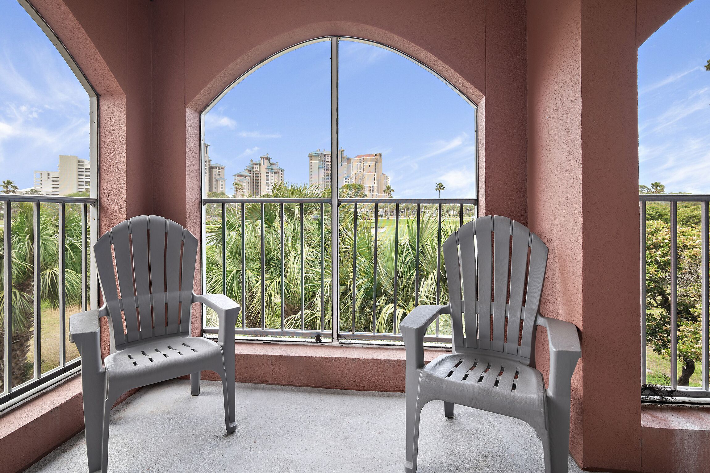 Un balcón con dos sillas Adirondack, vistas de la ciudad y un cielo despejado.