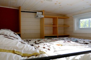 Ein Schlafzimmer mit einem Bett, Holzregalen und einem Fenster.