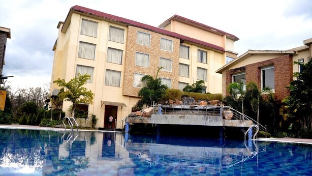 A hotel with a swimming pool, a stone bridge, and a building with multiple windows.