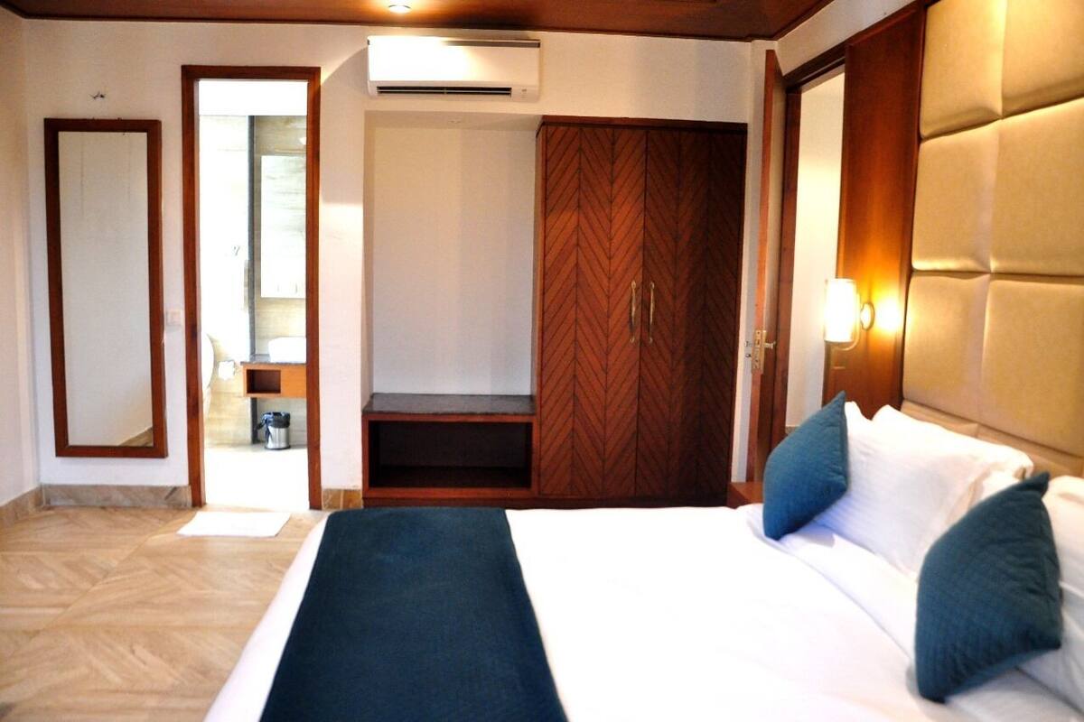 A hotel room with a bed, a wardrobe, a mirror, and an air conditioning unit.