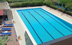 Una piscina al aire libre de temporada, sombrillas, tumbonas