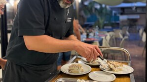 A person serving food at a counter with a tray of desserts and a cake with a lit candle. - Green Sporting Club Hotel (Alghero)