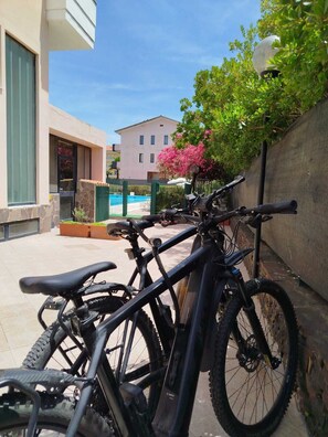 A bicycle parked next to a building with a pool in the background. - Green Sporting Club Hotel (Alghero)