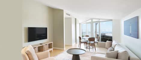 Una sala de estar moderna con un televisor de pantalla plana, un sofá, una mesa de centro y un comedor con sillas.