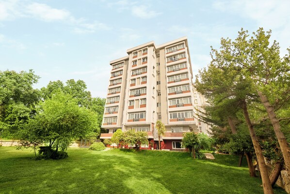 A multi-story residential building with a well-maintained lawn and trees in front. - The Marmara Çamlıca (Istanbul)
