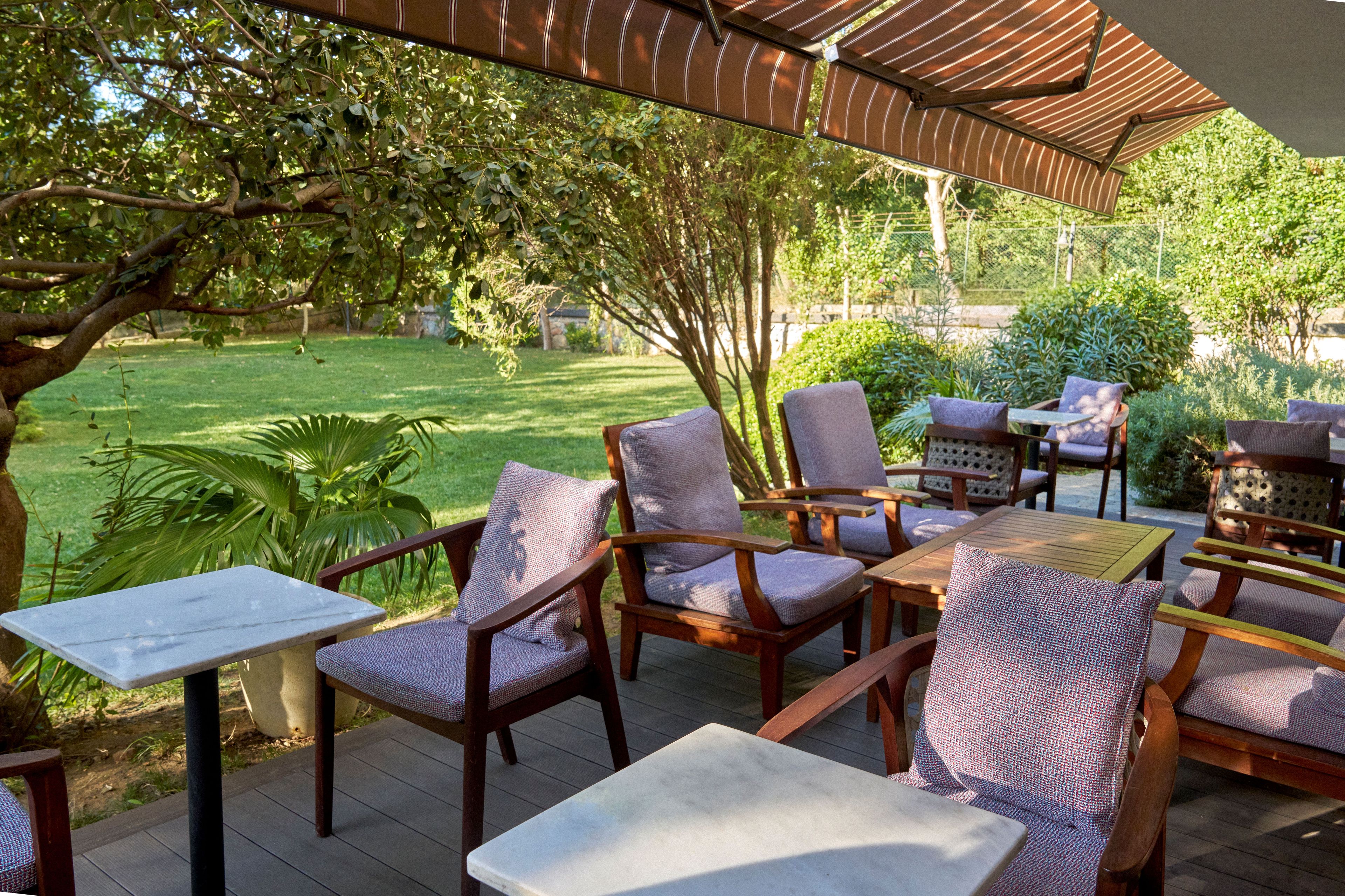 Eine Außenpatio-Terrasse mit Holzmöbeln und einer Pergola, die Schatten spendet.