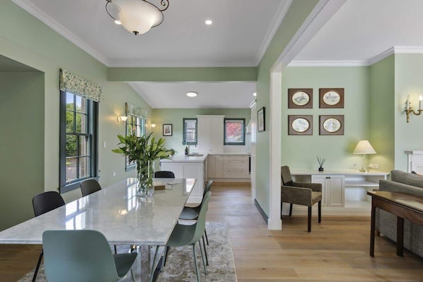 A spacious dining area with a long table, chairs, and a vase of flowers.