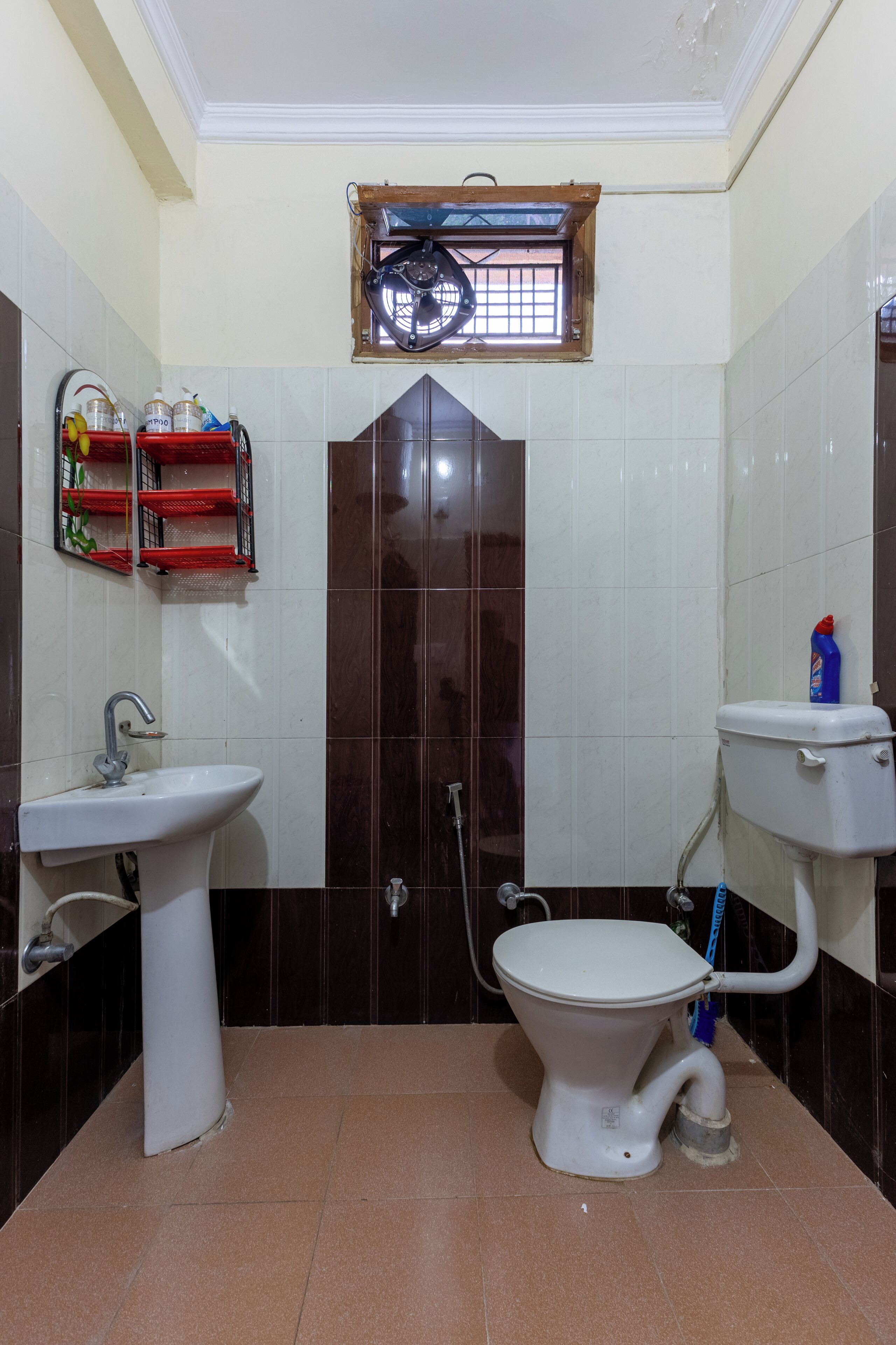 Une salle de bain avec un lavabo sur colonne, des toilettes et une fenêtre située au-dessus de la porte.