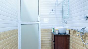 A bathroom with a toilet, sink, mirror, and shower.