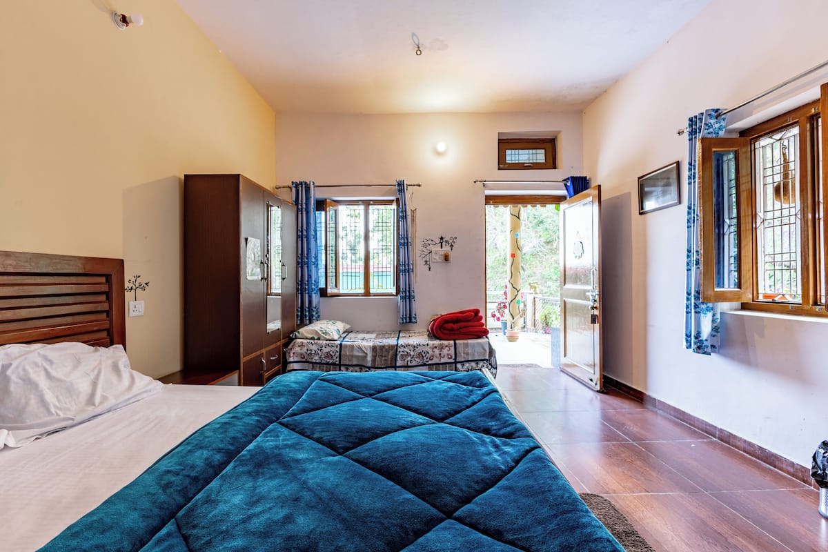 A bedroom with a bed, a wardrobe, a desk, and a window with curtains.