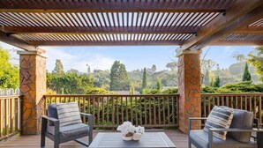 A covered outdoor seating area with stone pillars, a wooden pergola, and a view of a lush landscape. - Santa Barbara Mesa Home on the hill (Santa Barbara)