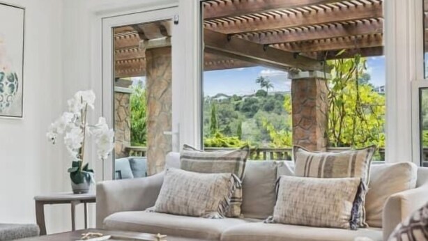 A cozy living room with a beige sofa, a wooden coffee table, and a view of greenery outside. - Santa Barbara Mesa Home on the hill (Santa Barbara)