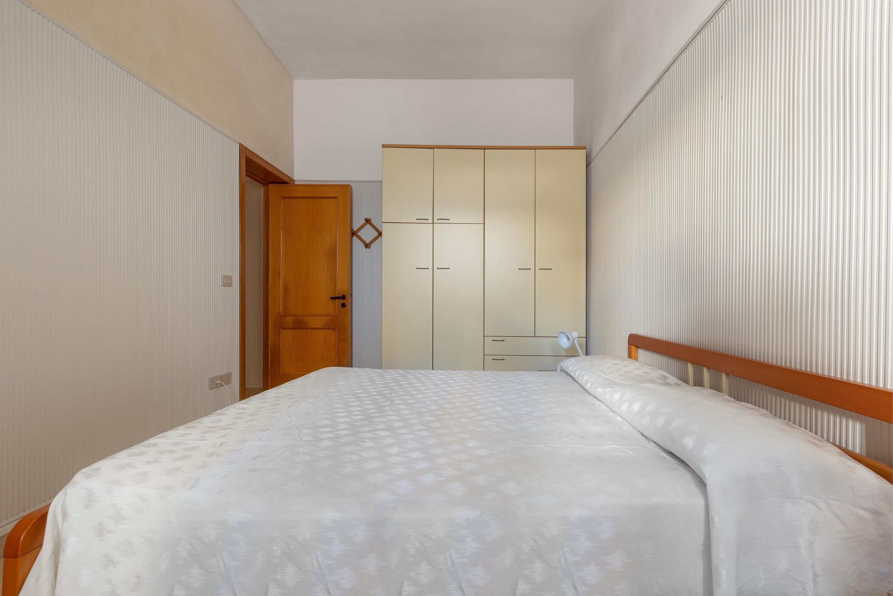 Un dormitorio con cama, armario y puerta.