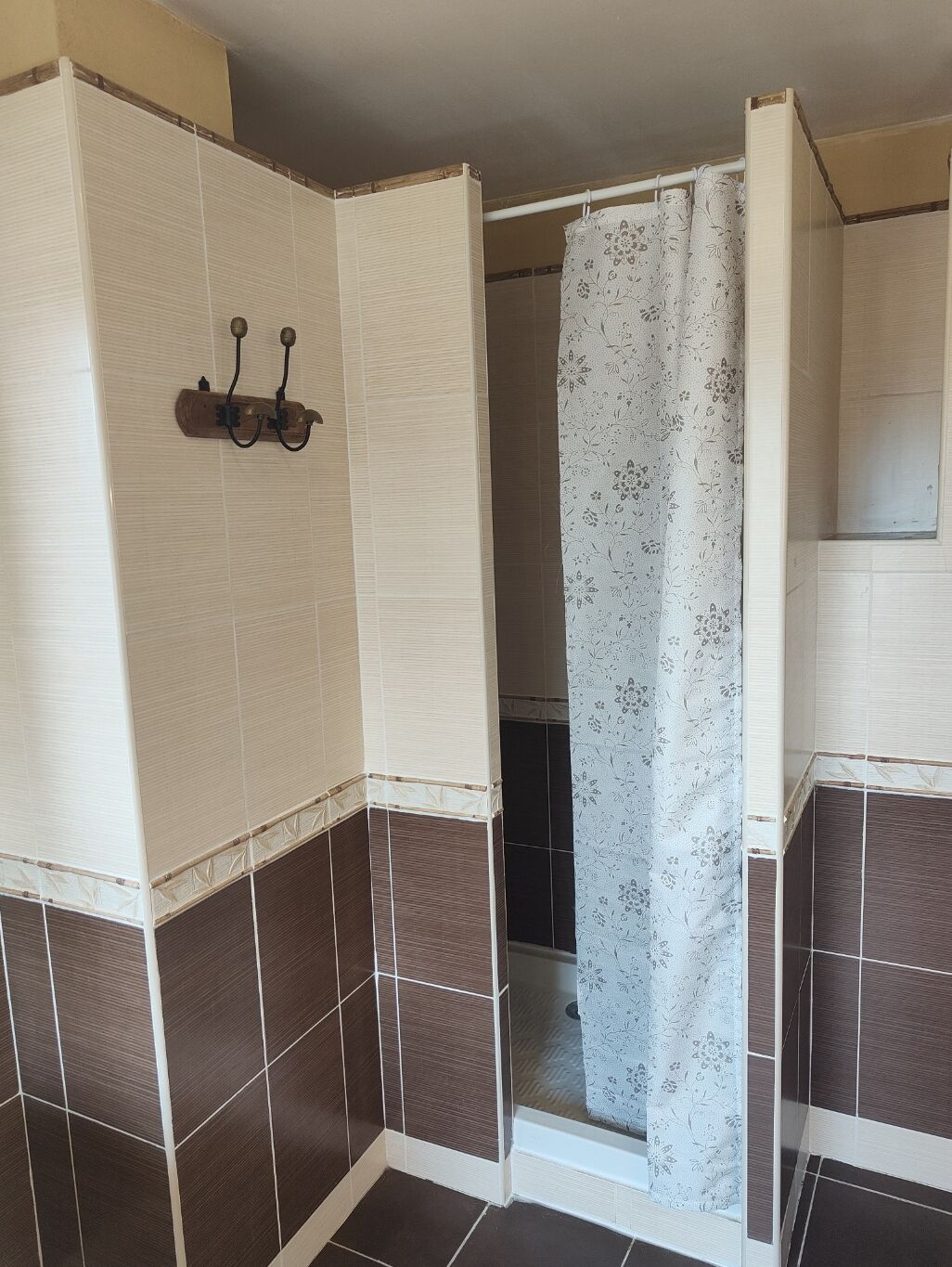 A bathroom with a shower area, tiled walls, and a towel rack.