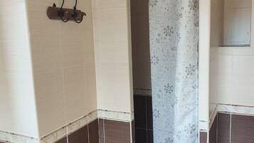 A bathroom with a shower area, tiled walls, and a towel rack.