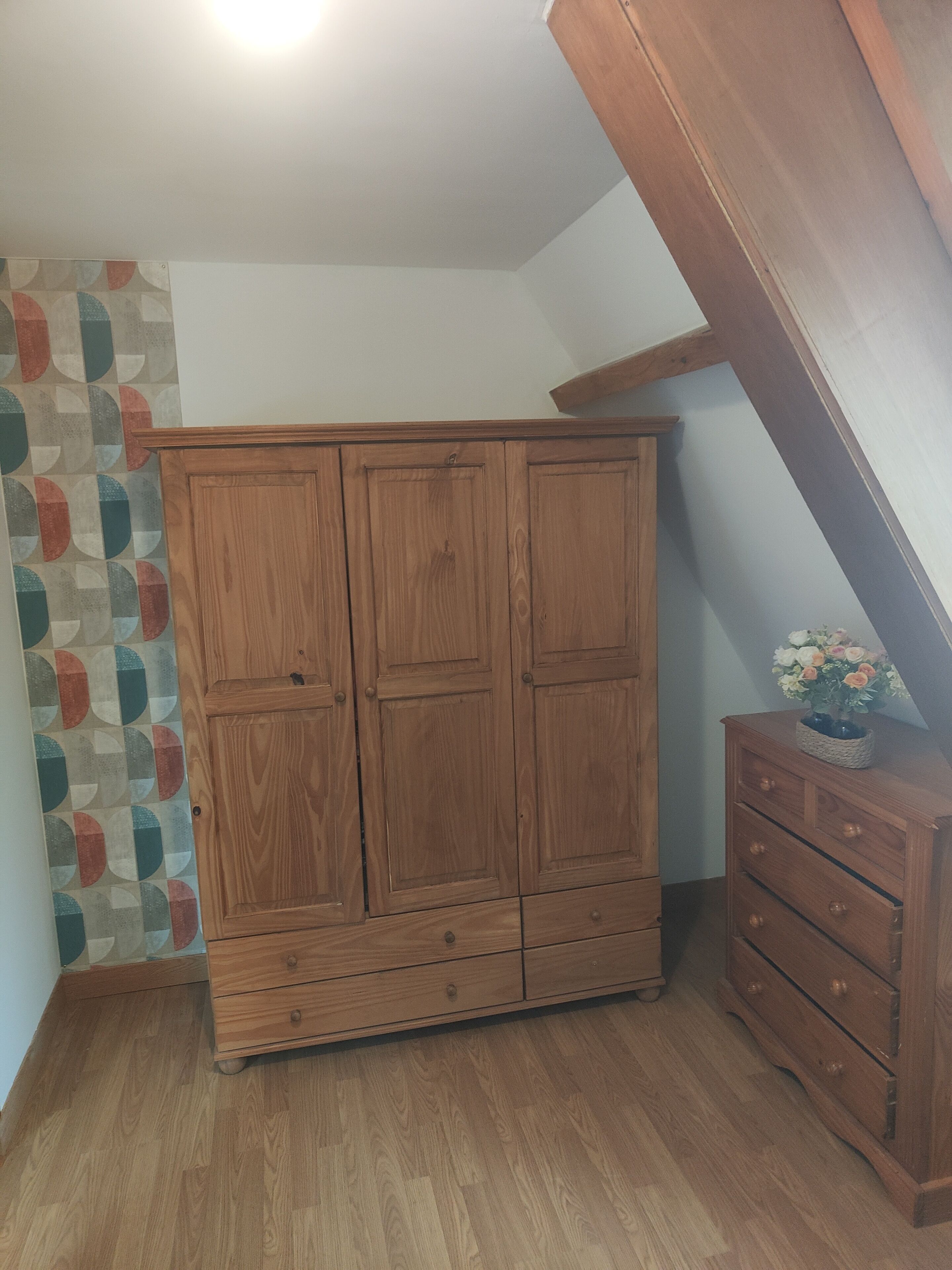 A wooden wardrobe with two doors and a small cabinet with drawers.