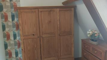 A wooden wardrobe with two doors and a small cabinet with drawers.