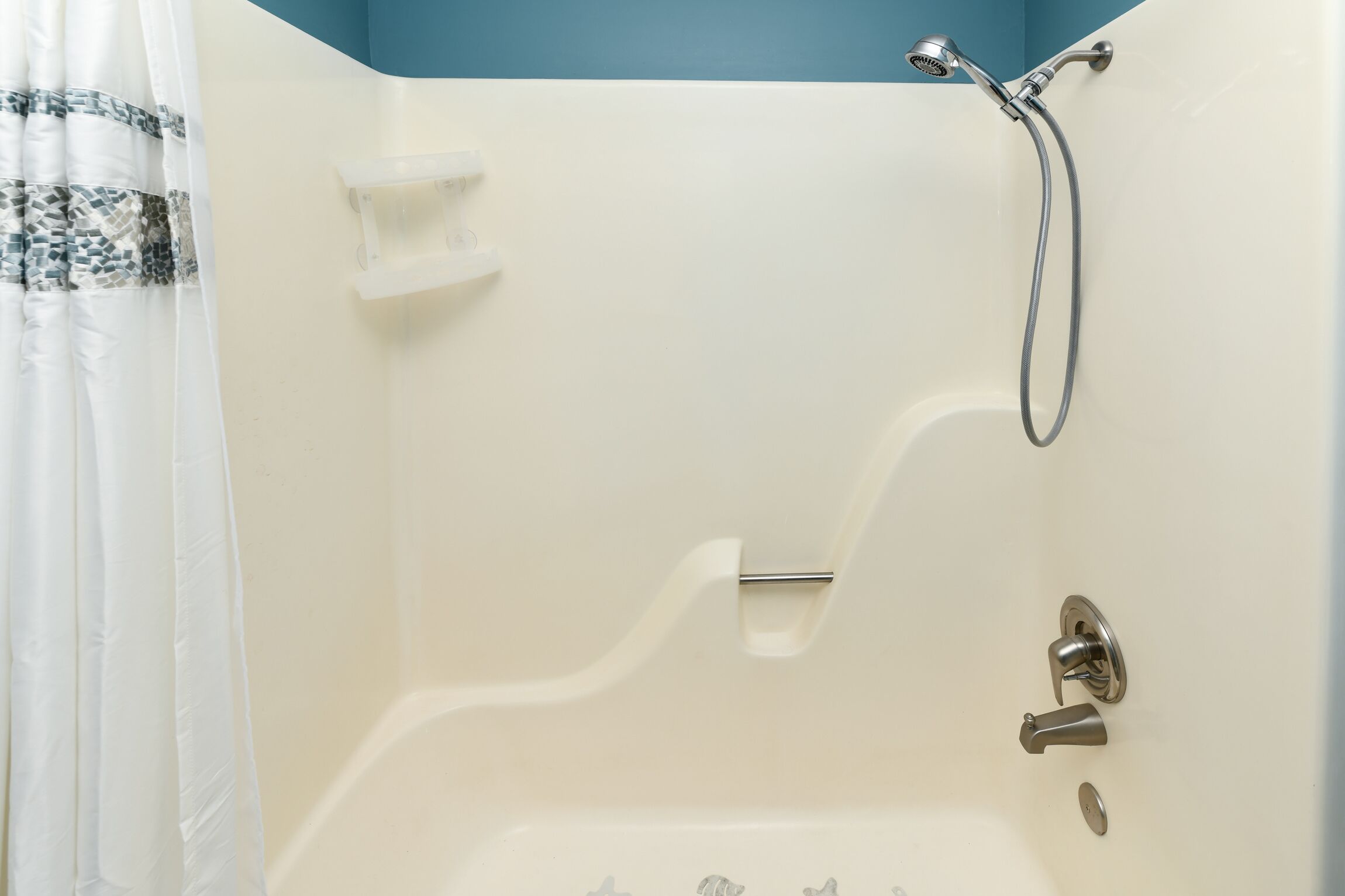 A shower area with a handheld showerhead, a wall-mounted faucet, and a soap dish.