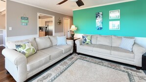 Un salon avec deux canapés beige, un tapis à motifs et des murs de couleur turquoise.