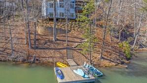 A lakeside property with a dock, a boat, and a multi-story house surrounded by trees. - Lakefront Home - Mountain Resort, Kayaks, SUP Boards, Game Rm (Lake Lure)