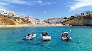 A coastal town with boats on the water, a beach, and buildings along the cliff. - Casa Mare Mio (Albufeira)