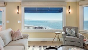 Une pièce avec vue sur l’océan, un canapé, un fauteuil et une petite table.