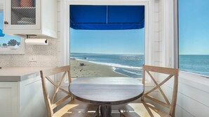 Une cuisine avec vue sur la plage, une table à manger et des chaises.