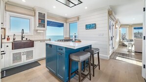 Une cuisine moderne dotée d’un îlot central, d’une grande fenêtre et d’une vue sur la mer.