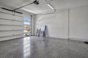 A clean, empty garage with a polished floor, a large garage door, and a ceiling-mounted projector.